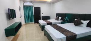 a hotel room with two beds with green curtains at Hotel Manoj in Bhopal +2 photos