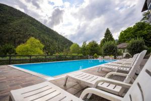 a group of white lounge chairs sitting next to a swimming pool at Residence CATULLO in Bezzecca
