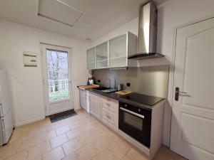 a kitchen with white cabinets and a black stove top oven at Escapade au Lac in Corancy