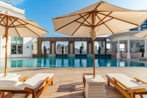 a pool with chairs and umbrellas in front of a building at Cape Racha Hotel in Si Racha