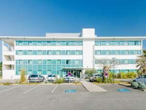 un grand bâtiment blanc avec des voitures garées dans un parking dans l'établissement B&B HOTEL Toulouse Basso Cambo, à Toulouse