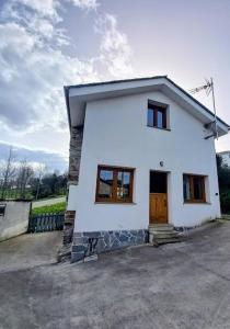 a small white house with a door and windows at Lar da avoa in Ouviaña