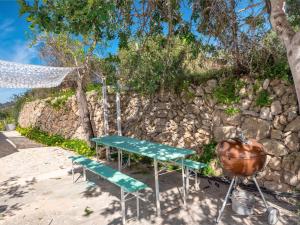 a picnic table and a grill next to a stone wall at Flor de Besso in Llucmajor