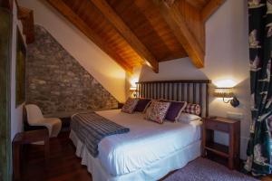 a bedroom with a bed and a stone wall at HOTEL EL Alboroque in Tramacastilla de Tena