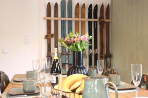 a table with a bottle of wine and a vase of flowers at Ferienhaus Ferienwohnung CasaBergZeit mit Königscard im Allgäu, Pfronten, Füssen in Pfronten