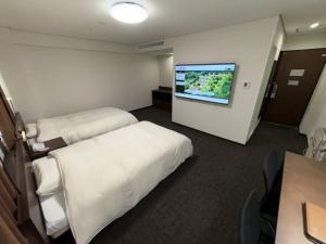 a hotel room with two beds and a flat screen tv at Hotel Alpha-One Niihama in Niihama