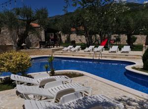 a pool with white lounge chairs next to a swimming pool at Villa Ponta in Kaluđerac