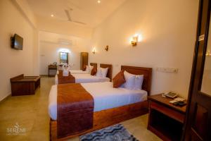 a hotel room with two beds and a television at Serene Lake View Resort in Anuradhapura