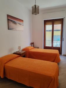 two orange beds in a room with a window at Appartamento Serenity in Marina di Ascea +3 photos