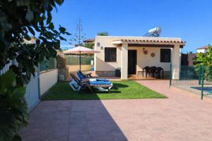 a yard with chairs and an umbrella and a house at Casa Lucia Conil in Conil de la Frontera