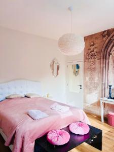 a bedroom with a pink bed with pink pillows on a table at La Villa Delsa in Namur