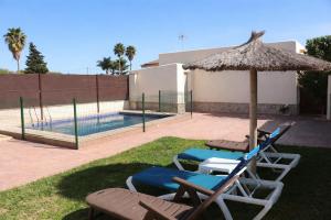 two lounge chairs and an umbrella next to a swimming pool at Casa Lucia Conil in Conil de la Frontera