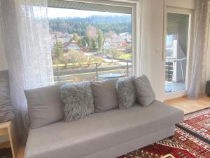 a couch in a living room with a large window at Gemütliche Wohnung mit Berg- und Waldblick in Balingen