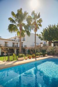 a swimming pool with palm trees and a building at Hotel Tossal d'Altea in Altea