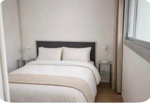 a white bedroom with a large white bed with two tables at Loft cosy au portes d'avignon in Les Angles Gard