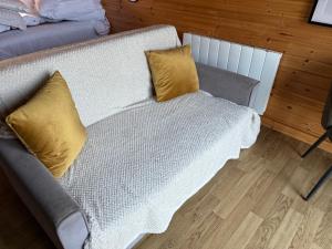 a white couch with two yellow pillows on it at Squirrel's Drey in Torphichen +2 photos
