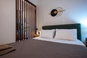 a bed with white pillows and a clock on the wall at Olea Blue Suite in Stalís