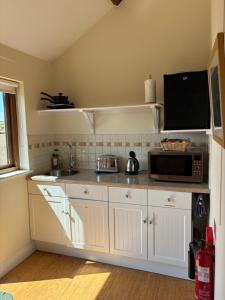 a kitchen with white cabinets and a microwave oven at Cool Contours Venue in Eydon