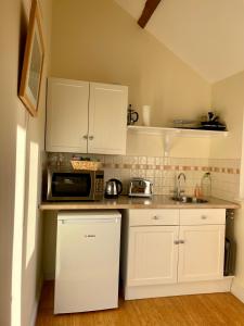 a kitchen with white cabinets and a microwave at Cool Contours Venue in Eydon +19 photos