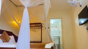 a bedroom with a bed with curtains and a television at Safari Homes in Kampala
