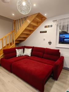 a red couch in a living room with a staircase at Clonakilty Cozy Nest in Clonakilty