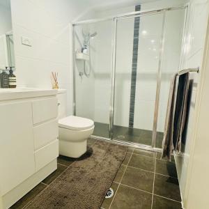 a white bathroom with a toilet and a shower at Casa de Burgh in Turner +5 photos