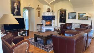 a living room with leather furniture and a fireplace at Csillaghy Kastély in Bókaháza +7 photos