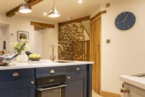a kitchen with blue cabinets and a clock on the wall at Beckside in Kettlewell +41 photos