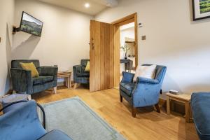 a living room with two blue chairs and a door at Beckside in Kettlewell