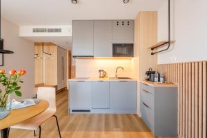 a kitchen with white cabinets and a wooden table at Akces APARTAMENTY KASPROWICZA 20C- BASEN, SAUNY, JACUZZI, SIŁOWNIA W CENIE - SCHWIMMBAD, SAUNEN, JACUZZI, FITNESSSTUDIO IM PREIS in Kołobrzeg
