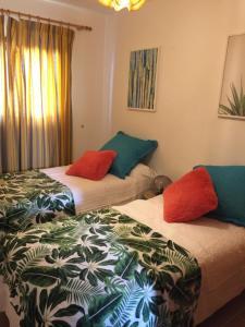 two beds in a hotel room with red pillows at Casa Corralejo a 40 m playa in Corralejo