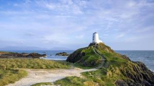 a lighthouse on top of a hill near the ocean at Ty Will, Parc Y Fronwen in Newborough