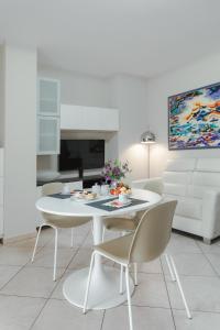 a white living room with a white table and chairs at Brezza di Mare Apartment in Scanzano +12 photos