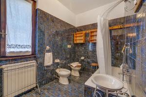 a blue tiled bathroom with a toilet and a sink at Villa Eva: Leggiuno 5-Bed Villa for Families & Groups (Sleeps 10) - Happy Rentals in Leggiuno