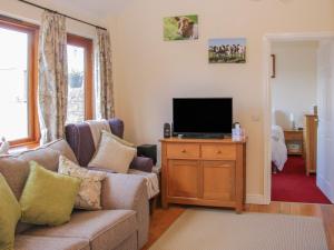 a living room with a couch and a flat screen tv at Herdwick Cottage in Much Wenlock