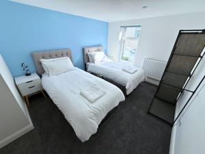 two beds in a room with blue walls at New 3 Bedroom Flat Close to Station in Chepstow