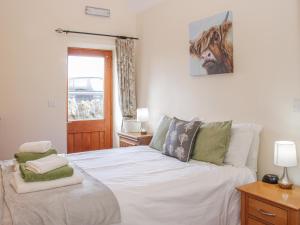 a bedroom with a large white bed with green pillows at Herdwick Cottage in Much Wenlock