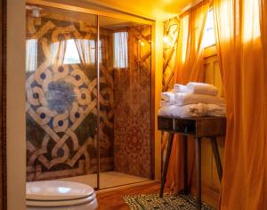 a bathroom with a shower and a pile of towels at 2 CUORI E 1 YURTA Glamping in Tuscany - Adults Only in Asciano