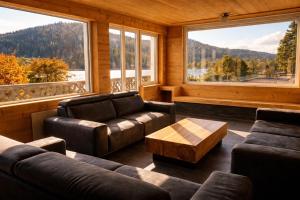a living room with leather furniture and large windows at Domusigua in Gérardmer