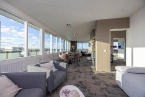 ein Wohnzimmer mit Sofas, einem Tisch und Fenstern in der Unterkunft Fletcher Hotel - Restaurant Elzenduin in Ter Heijde