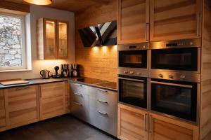a kitchen with wooden cabinets and stainless steel appliances at Domusigua in Gérardmer
