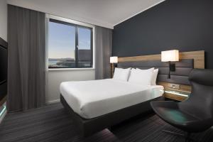 a hotel room with a bed and a chair and a window at Moxy Southampton in Southampton