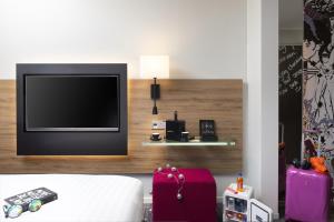 a room with a tv and a bed and luggage at Moxy Southampton in Southampton