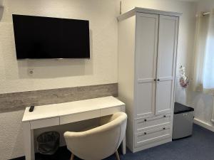a room with a desk and a tv on a wall at Gästehaus Elzblick in Rust