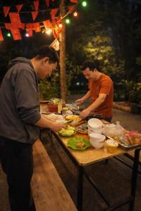 two men standing around a table preparing food at HangNga homestay - hotel in Phủ Từ Sơn