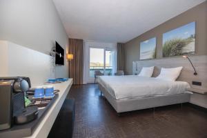 ein Hotelzimmer mit Bett und Schreibtisch mit Fernseher in der Unterkunft Fletcher Hotel - Restaurant Elzenduin in Ter Heijde + 70 Fotos