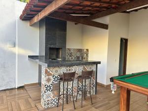 a patio with a fireplace and a pool table at Casa Verano dHebron in Camaçari