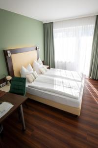 a hotel room with a large bed and a desk at Gästehaus am Räuschenberg in Höxter