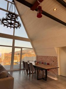 a dining room with a table and chairs and large windows at SkyHouse Shahdag in Əniq