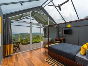 a room with a bed and a balcony with a tub at The Hosteller Bam Vagamon in Vagamon